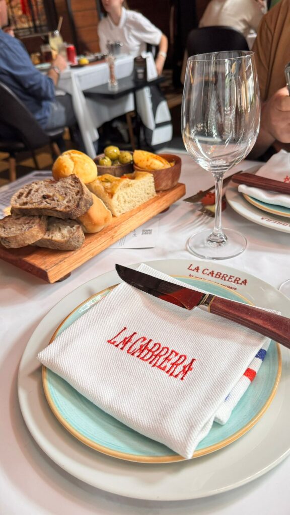 Mesa posta na La Cabrera revela o cuidado com os detalhes, da louça personalizada aos pães artesanais servidos logo no início da experiência.